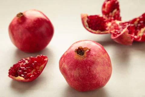 A whole pomegranate and a half-cut pomegranate with seeds on light background Stock Photos