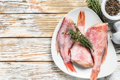 Whole raw red snapper fish on a plate. White wooden background. Top view. Copy Stock Photos
