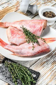 Whole raw red snapper fish on a plate. White wooden background. Top view Stock Photos