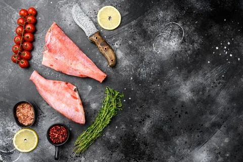 Whole raw red snapper fish, on black dark stone table background, top view fl Stock Photos