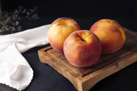 Whole ripe peaches (Prunus persica) on rustic cutting board. Close up image Stock Photos