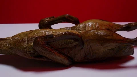 Whole roasted duck rotating on white table red background Stock Footage 328084829