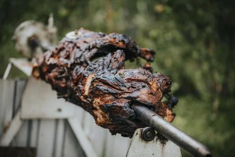 Whole roasted lamb on a spit, displaying charred exterior and juicy texture.. Stock Photos