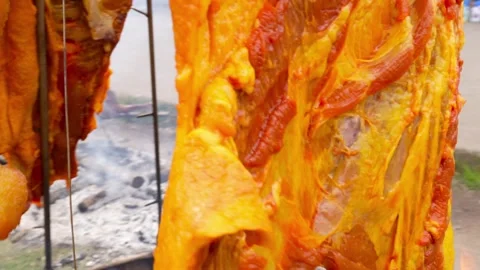 Whole roasted meat grilling on fire at Pillaro County Fair, Ecuador Stock Footage 310191825