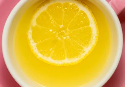 A whole slice of lemon floating in tea or lemonade in a pink mug Stock Photos