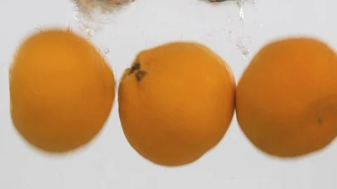 Whole tangerines falls into the water with bubbles. Slow motion. Stock Footage 126800876