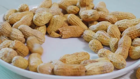 Whole Unshelled Peanuts Stacked on White Ceramic Plate Stock Footage 346108451