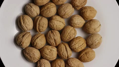 Whole walnuts arranged on rotating white plate top view Stock Footage 327909803