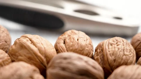 Whole walnuts with a nutcracker. Close-up of textured brown shells. Stock Footage 303338955