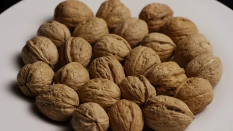 Whole walnuts rotating in circle on white plate view Stock Footage 327909798
