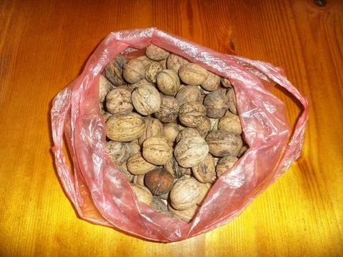 Whole Walnuts In Shell Inside Plastic Bag On Wooden Table Background Foto stock