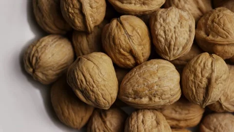 Whole walnuts in shell rotating on white plate Stock Footage 328135672