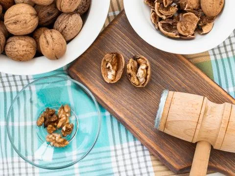 Whole walnuts, shells and kernels in a bowls around a brown wooden board. Stock Photos