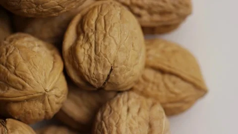 Whole walnuts in shells rotating on a white surface Stock Footage 327829228