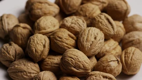 Whole walnuts in shells rotating on a white background Stock Footage 327829232