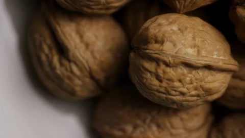 Whole walnuts with shells on white plate panning view Stock Footage 327829634