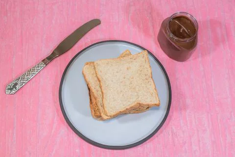 Whole wheat bread loaf slice in plate have chocolate on pink background. Stock Photos