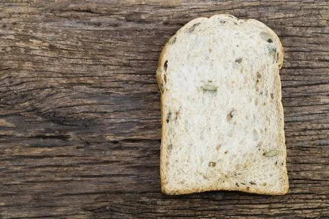 Whole wheat bread slice have rice grain on wood background. Stock Photos