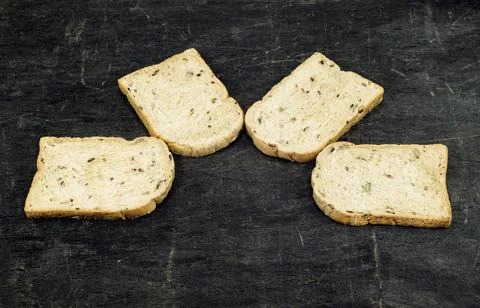 Whole wheat bread slice have rice grain on black wood background. Stock Photos