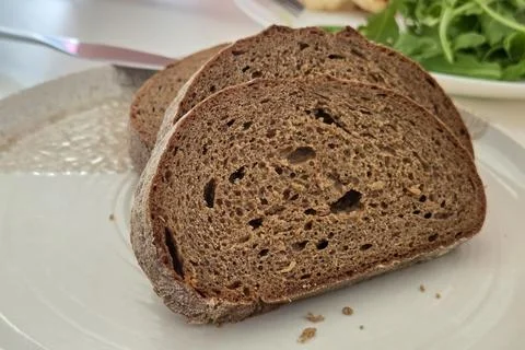 Whole wheat bread slices on a ceramic plate, styled with a leafy green salad  Stock Photos