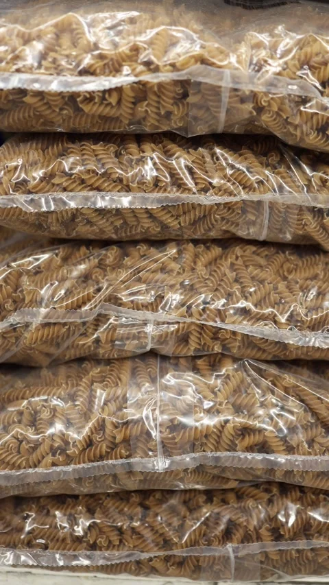 Whole wheat fusilli pasta packed in large clear plastic bags for retail Stock Footage 345977988