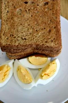 Whole wheat slice toasted bread with sliced boiled egg on the white plate for Foto stock