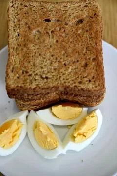 Whole wheat slice toasted bread with sliced boiled egg on the white plate for Foto stock