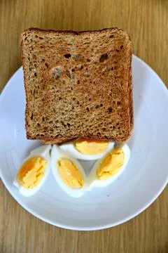Whole wheat slice toasted bread with sliced boiled egg on the white plate for Foto stock