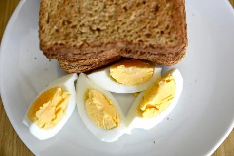 Whole wheat slice toasted bread with sliced boiled egg on the white plate for Foto stock