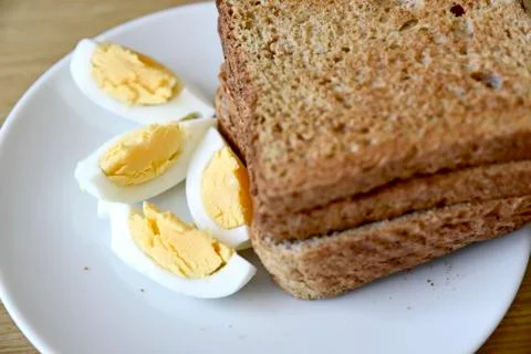 Whole wheat slice toasted bread with sliced boiled egg on the white plate for Foto stock