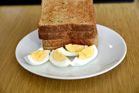 Whole wheat slice toasted bread with sliced boiled egg on the white plate for Foto stock