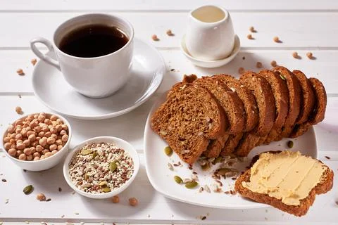 Wholegrain bread with chickpea paste on a white plate and a cup of coffee on Stock Photos