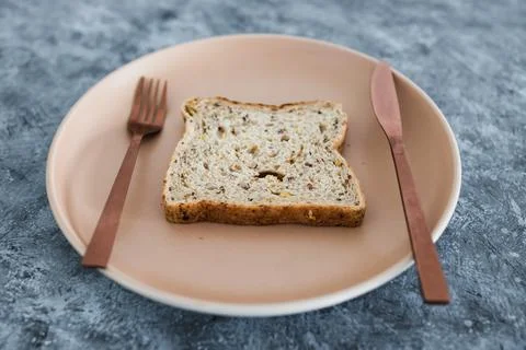 Wholegrain multiseeds slice of bread on dining plate with fork and knife, die Stock Photos