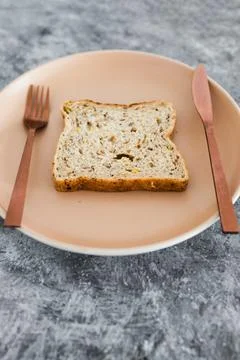 Wholegrain multiseeds slice of bread on dining plate with fork and knife, die Stock Photos