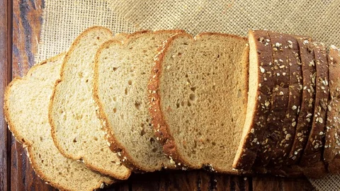 Wholegrain sliced organic bread composed of oats and flax seeds on wooden tab Stock Footage 104580652
