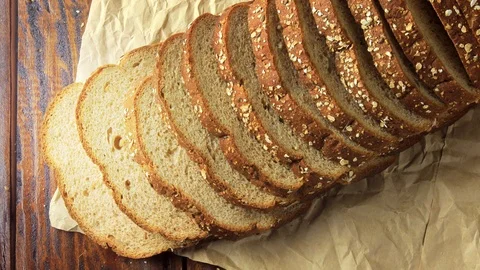 Wholegrain sliced organic bread composed of oats and flax seeds on wooden tab Stock Footage 104580655