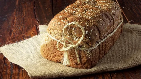 Wholegrain sliced organic bread composed of oats and flax seeds on wooden tab Stock Footage 104580899