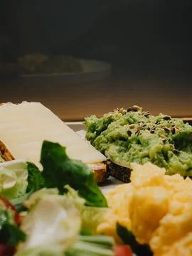 Wholemeal bread toasts with mashed avocado and cheese, scrambled eggs and fresh Foto stock