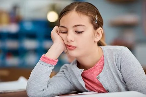 Why isnt it recess yet. a young elementary school girl looking bored while Stock Photos