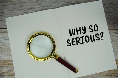 Why so Serious? text on notebook page with magnifying glass top view on woo.. Stock Photos