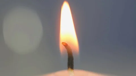 The wick burns close up. White candle on a blue background Stock Footage 123714214