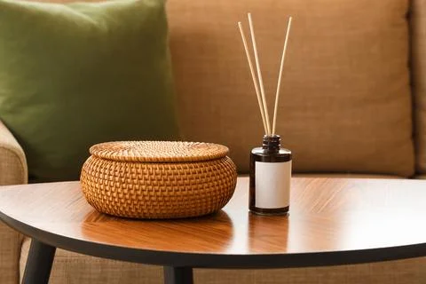 Wicker basket and reed diffuser on wooden table Stock Photos