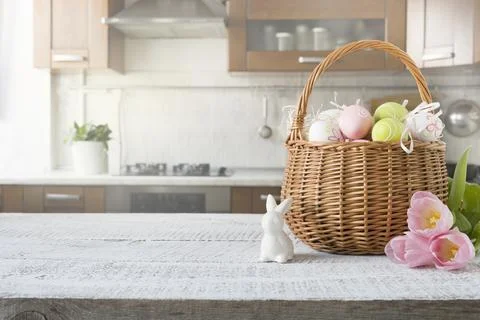 Wicker basket with bunny, tulip, easter colorful eggs on kitchen wooden tab.. Stock Photos