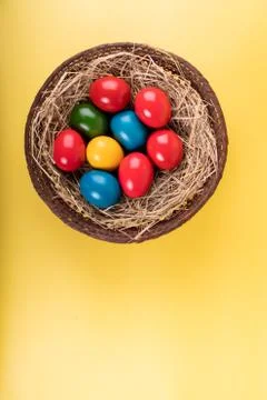 Wicker basket of colorful Easter eggs isolated on yellow Stock Photos