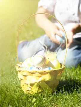 A wicker basket with colorful Easter eggs on a green lawn. Stock Photos
