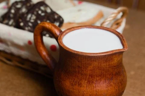 Wicker basket with different sliced bread and a jug of milk on the table. Hom Stock Photos