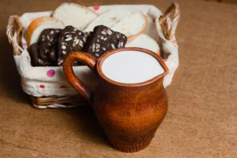 Wicker basket with different sliced bread and a jug of milk on the table. Hom Stock Photos