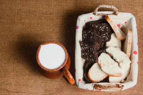 Wicker basket with different sliced bread and a jug of milk on the table. Hom Stock Photos