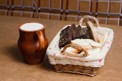 Wicker basket with different sliced bread and a jug of milk on the table. Hom Stock Photos