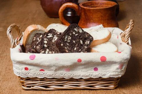 Wicker basket with different sliced bread. On the background of the pitcher.  Stock Photos